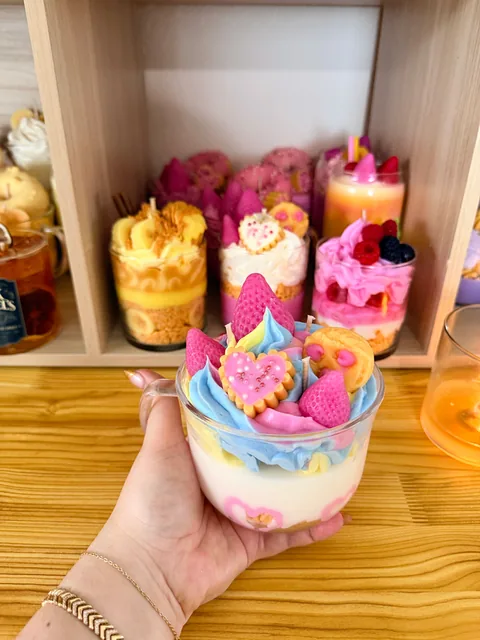 Vela en vaso con capas claras, cubierta azul y decoraciones rosas y amarillas
