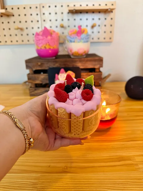 Vela con forma de pastel, cubierta rosa y decoraciones de frutos rojos