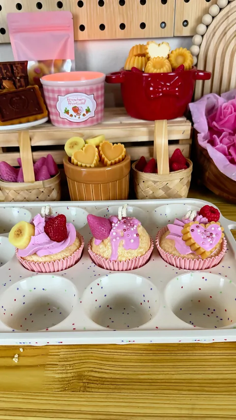 Exhibición de velas decorativas en tazas, moldes y formas de pequeños postres
