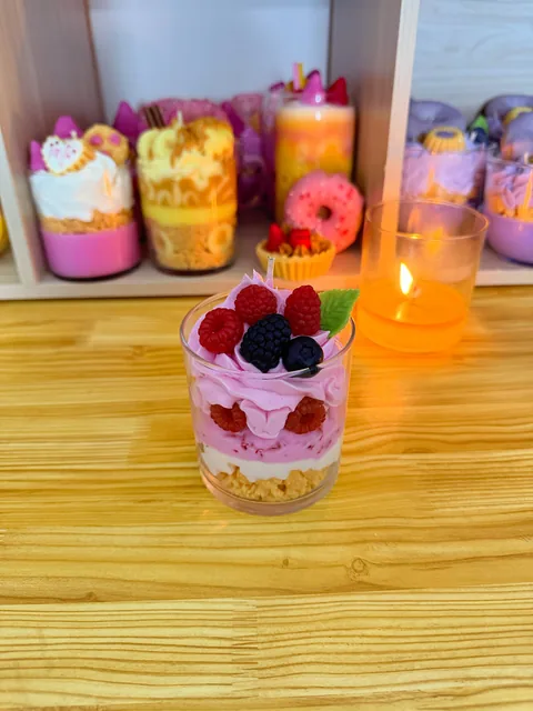Vela en vaso con capas rosas y claras, decorada con frutos rojos y oscuros