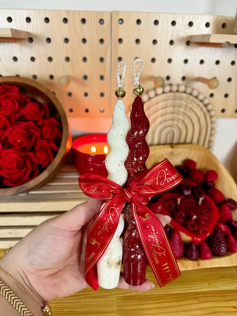 Dos velas altas retorcidas, blanca y roja, unidas con un lazo rojo.